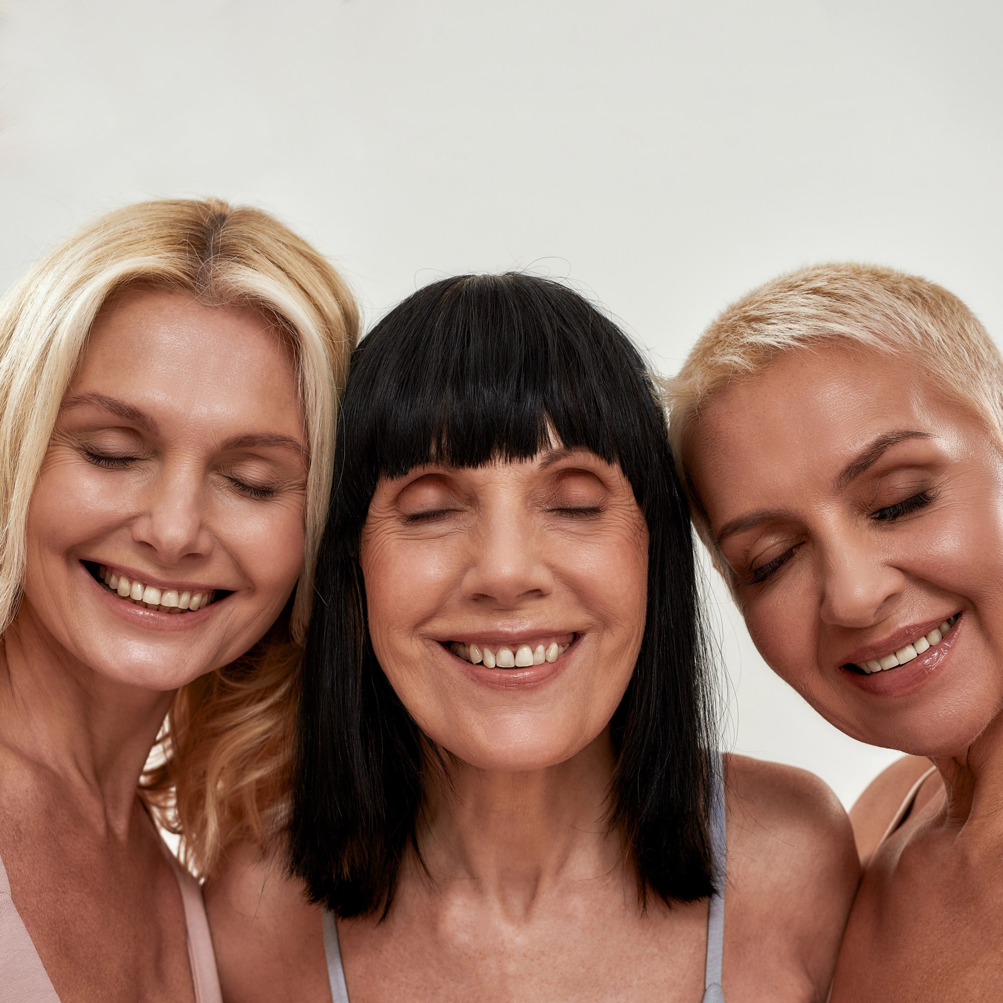 Three women smiling with their eyes closed
