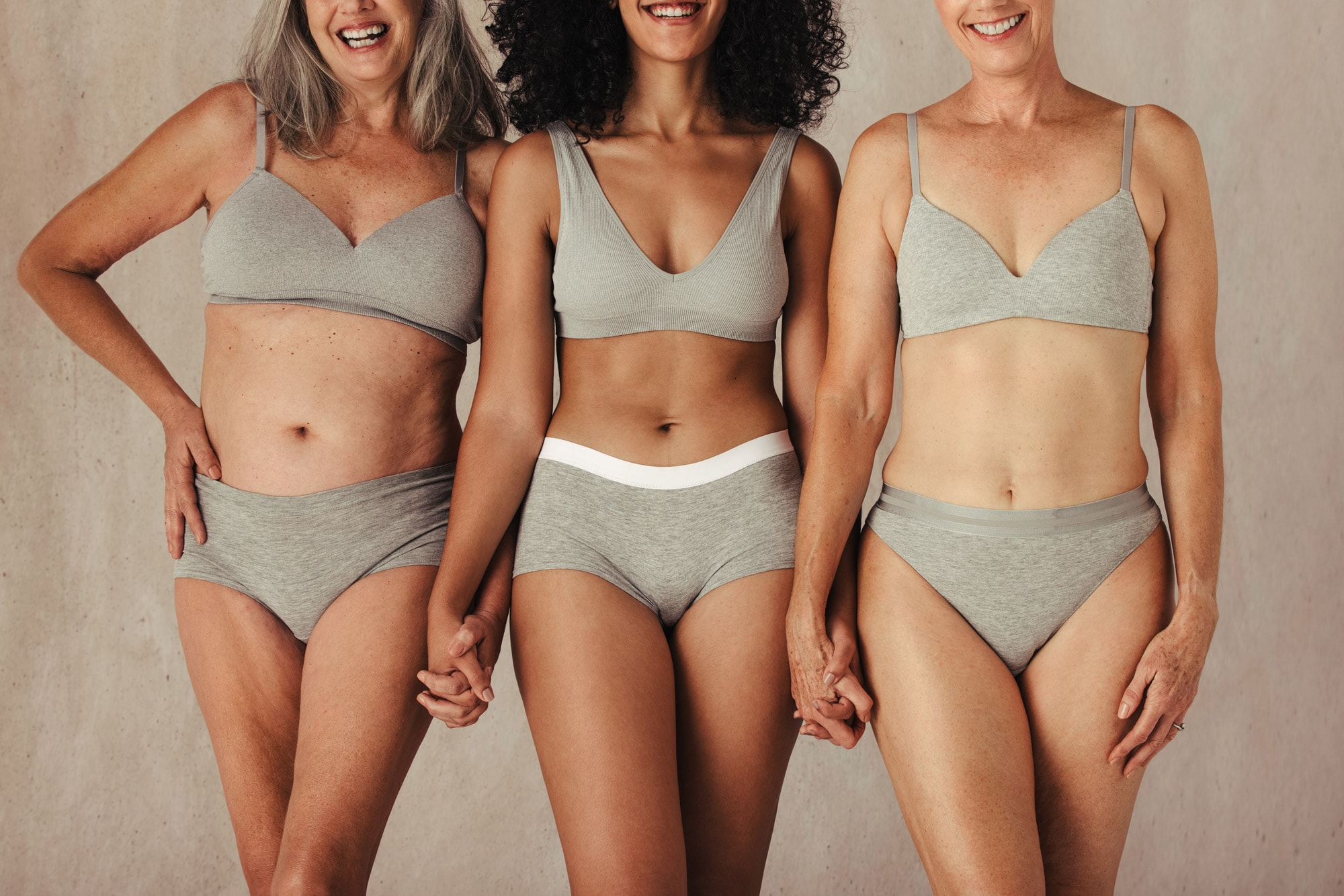 Three women in grey undergarments facing forward