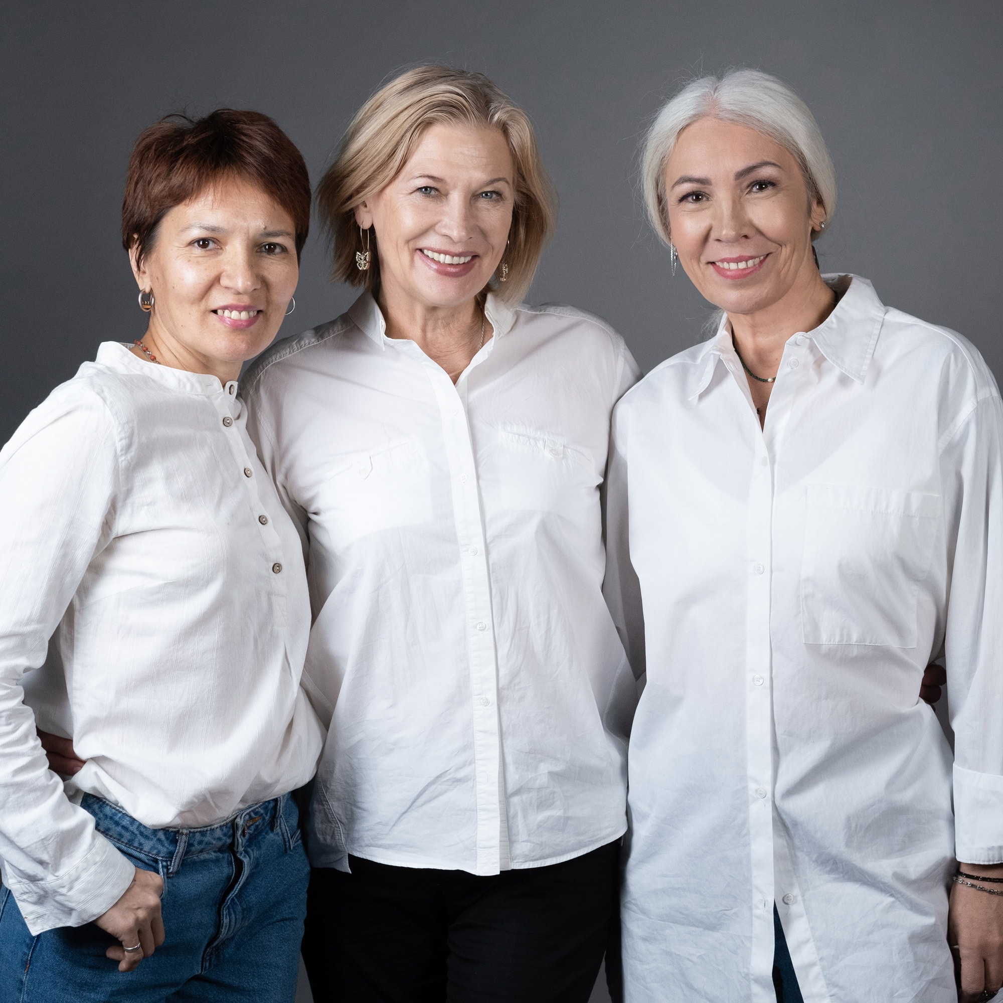 Three mature women smiling and wearing white dress shirts